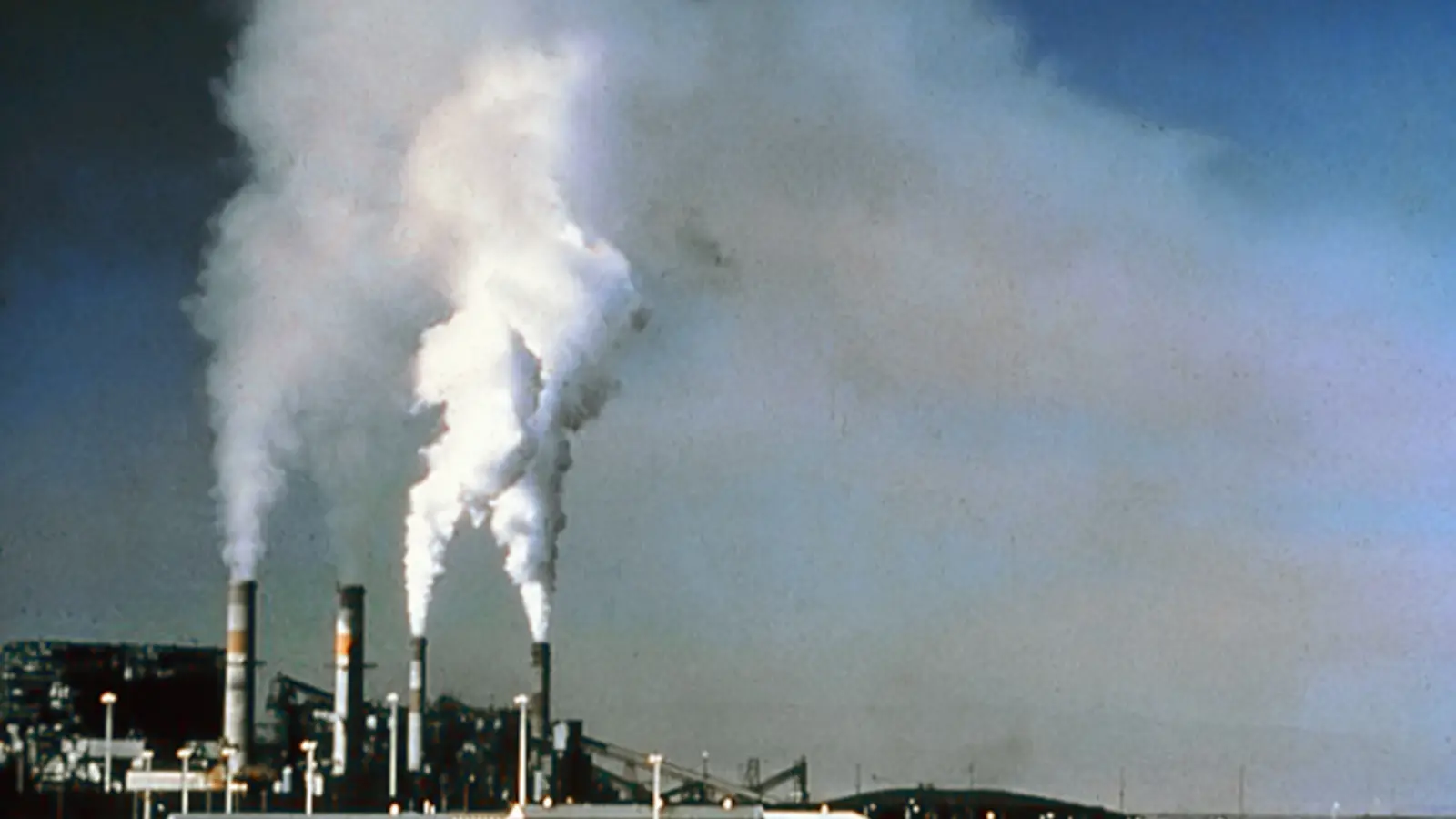 Industrial chimneys release emissions above a power station.