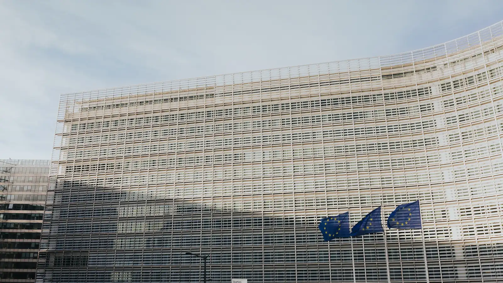 The Berlaymont building in Brussels, seat of the European Commission, with EU flags outside.