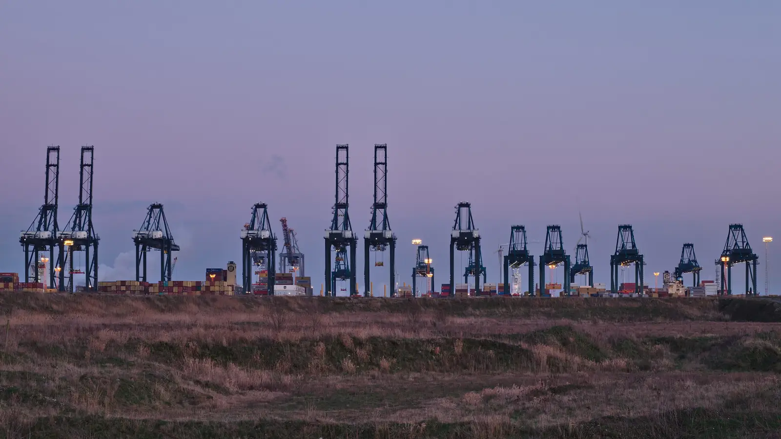 Container cranes at the MPET terminal in the port of Antwerp at dusk.